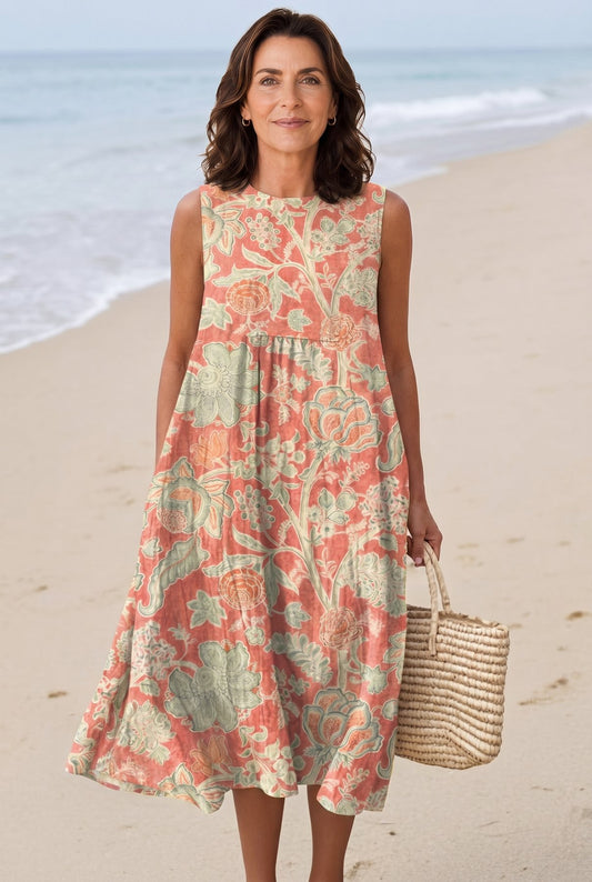 The Barbara Evening Dress in coral and sage abstract botanical print, full-length editorial beach setting