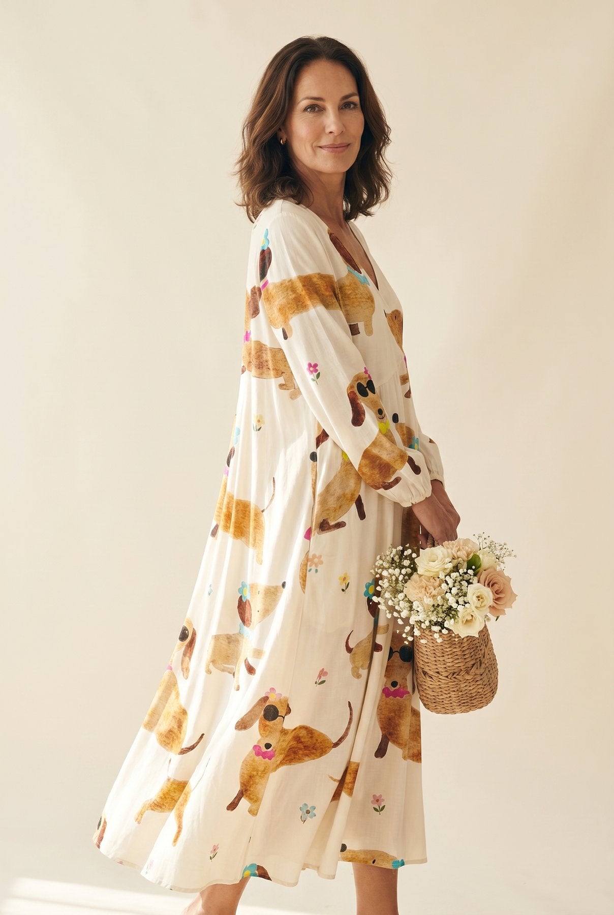The Carol Afternoon Dress in whimsical dog illustration print on cream, V-neck wrap maxi with puff sleeves, cream studio editorial with flower basket