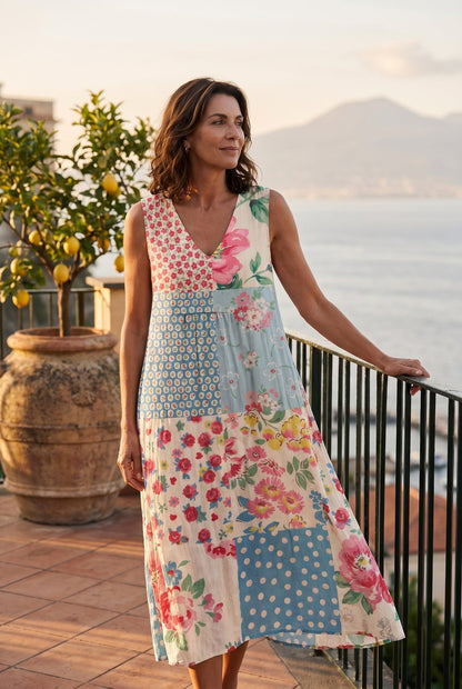 The Carolyn Resort Dress in soft floral and polka-dot patchwork, editorial full-body on a Sorrento terrace at golden hour with Bay of Naples behind