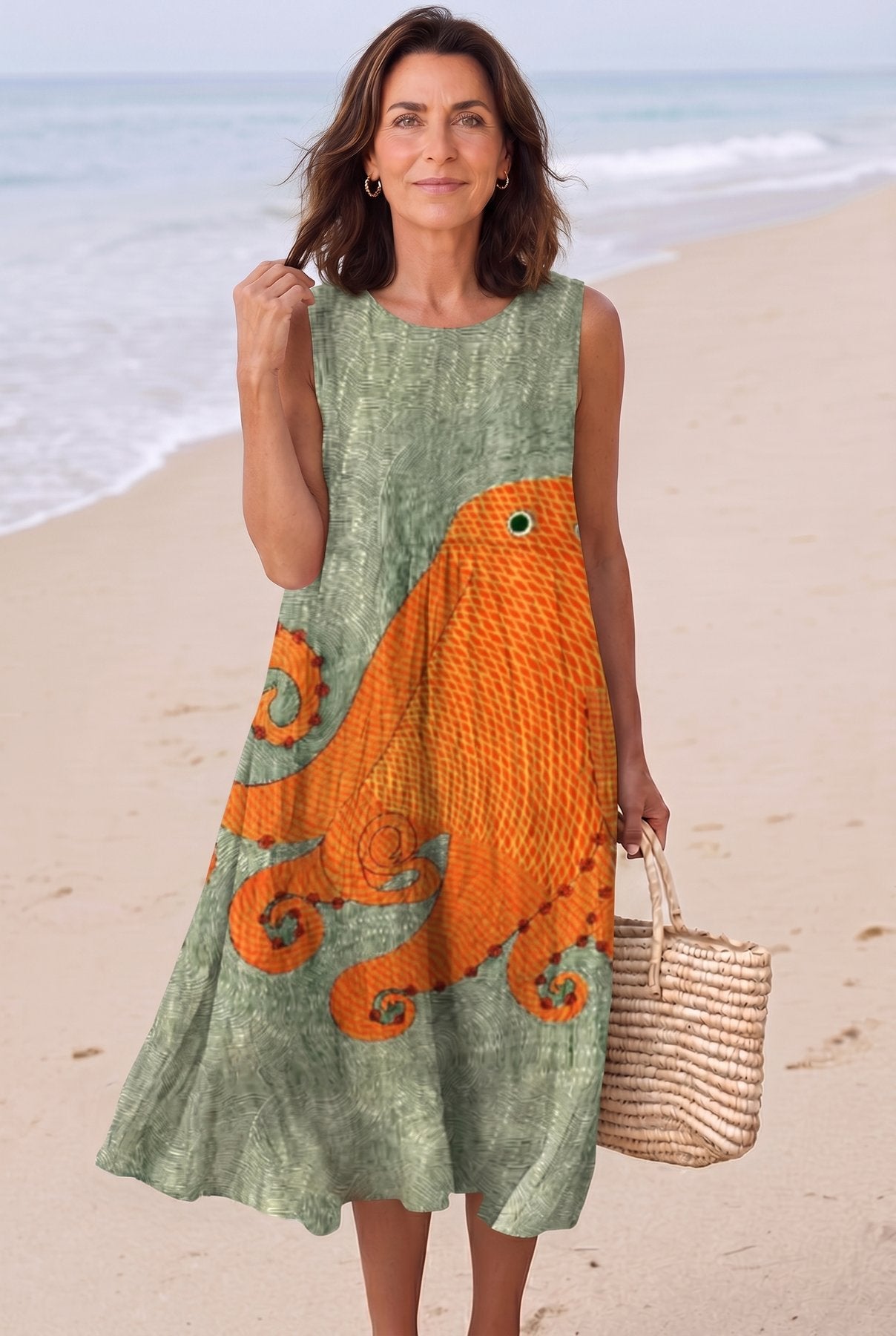 The Catherine Vacation Dress in orange octopus print on sage green, full-length editorial on a Mediterranean beach with woven basket