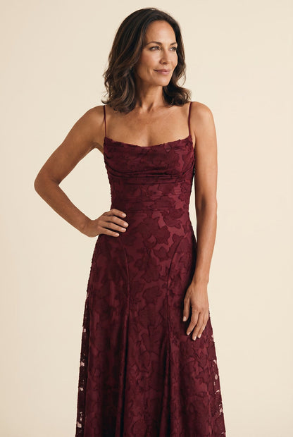 The Cynthia Ceremony Dress in cherry burgundy, candid editorial angle with hand on hip
