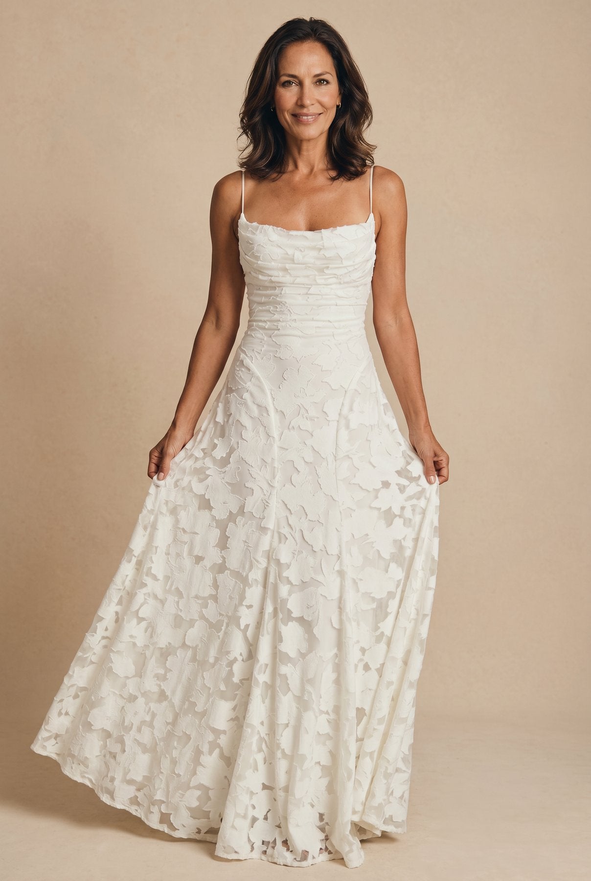 The Cynthia Ceremony Dress in ivory cream, holding the skirt to show the lace cutwork drape