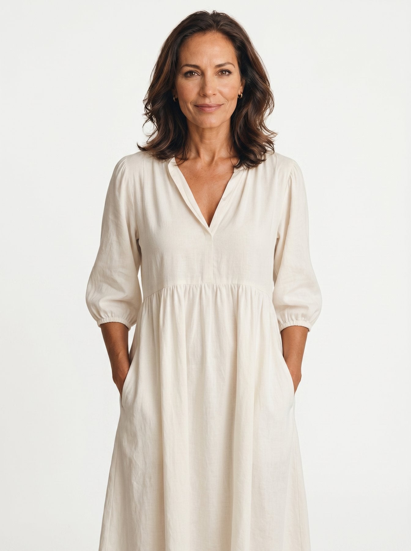 The Diane Sundress in ivory cream linen with V-neck and three-quarter puff sleeves, hands tucked in pockets