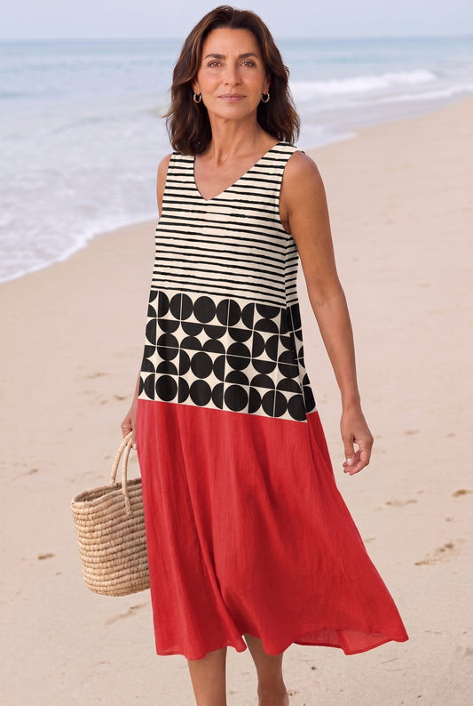The Mary Boat Dress in graphic stripes-and-dots with red color-block, full-length editorial on a Mediterranean beach with woven basket